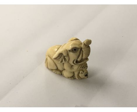 A Japanese carved Ivory Netsuke in the form of an elephant and a monkey signed base,