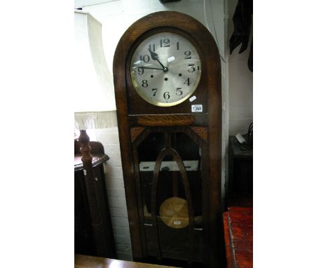 An oak 1930s longcase clock with visible pendulum and weights,