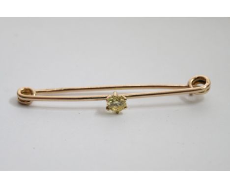 A gold stick pin set with a yellow diamond