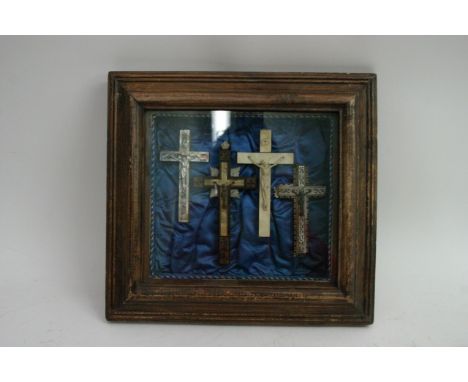 A cased framed set of four late Victorian crucifix comprising two mother of pearl, one painted and inlaid example and an anot