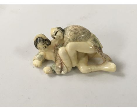 A Japanese carved Ivory Netsuke with applied colour decoration in the form of an amorous couple,