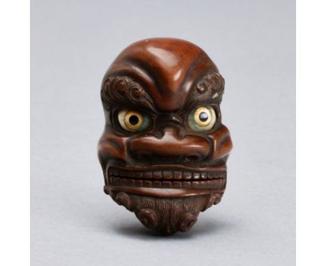 Masken-NetsukeJapan, 19. Jahrhundert. Holz, geschnitzt. 4,7 x 3,2 x 2,2 cm. Verso sign. Leicht ber. u. best., Zunge in Kopf g