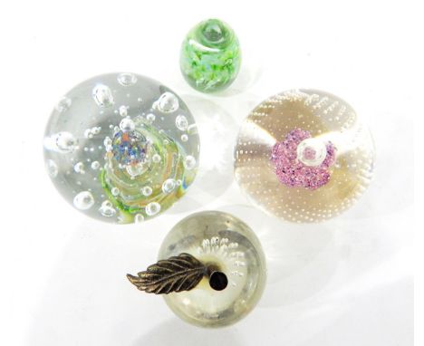 Glass paperweight, with central pink flower decoration, four further glass paperweights, one in the form of an apple, a colou