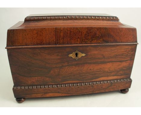 A 19th century rosewood tea caddy of sarcophagus form, the interior fitted with a well with cut glass bowl flanked by two lif