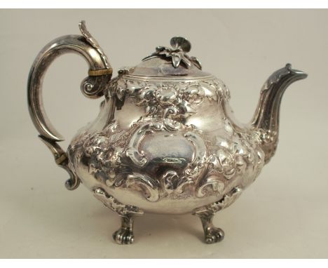 A Victorian silver teapot, with embossed decoration and flower finial, engraved with a crest, raised on four scroll feet, Lon