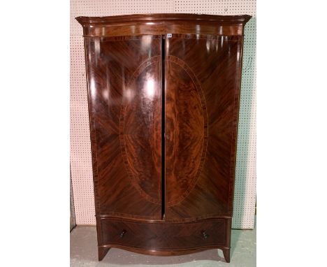An Edwardian mahogany serpentine double wardrobeWith a singe drawer base on splayed bracket feet, 120cm wide; 208cm high