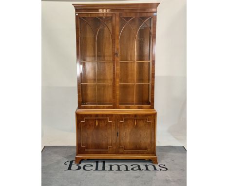 A George III style yew wood display cabinet.With moulded panelled doors on bracket feet, 101cm wide; 197cm high