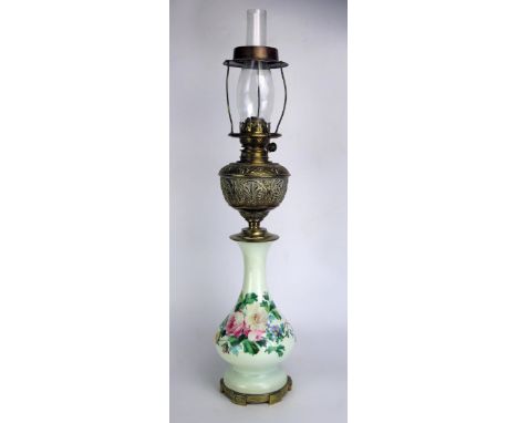 A Victorian brass and glass oil lamp, with embossed brass reservoir mounted on a green glass and floral decorated baluster st