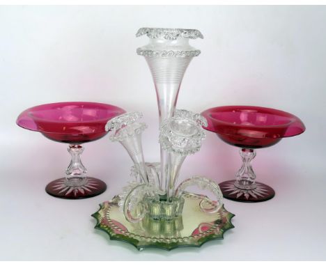 A glass epergne with central trumpet-shaped vase, with three smaller trumpet-shaped vases, on a shaped circular mirror plate 