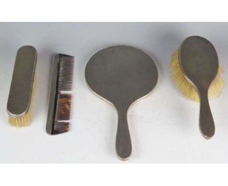 A silver backed matched four piece dressing table set, includes hair brush, hand mirror, comb and clothes brush with engine d