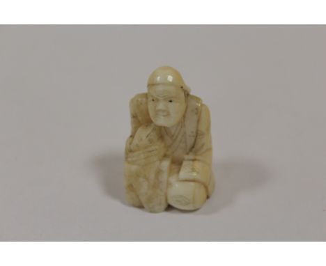 A VINTAGE NETSUKE IN THE FORM OF A KNEELING MAN 
