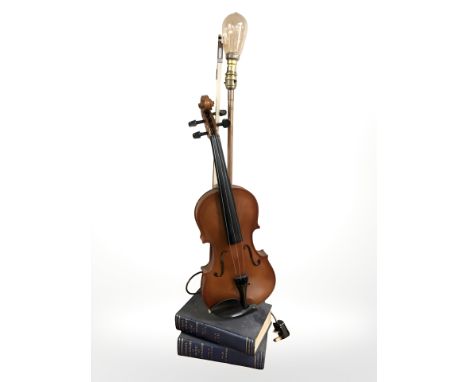 A contemporary table lamp in the form of a violin on a stack of books.