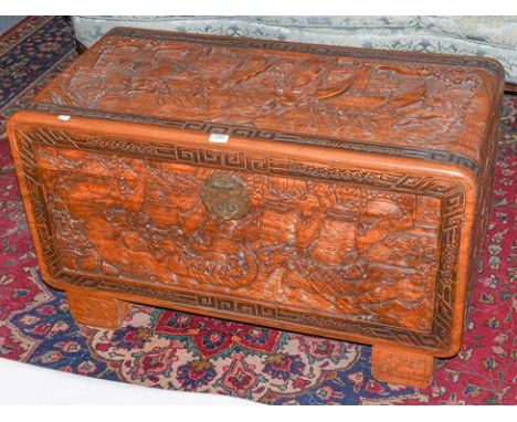 ~ A 20th century oriental carved camphor wood trunk, decorated to in relief with boating scenes, 100cm by 50cm by 58cm 