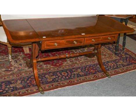 A regency mahogany two-drawer sofa table, banded in satinwood and with strung inlay, turned cross stretcher and brass castors