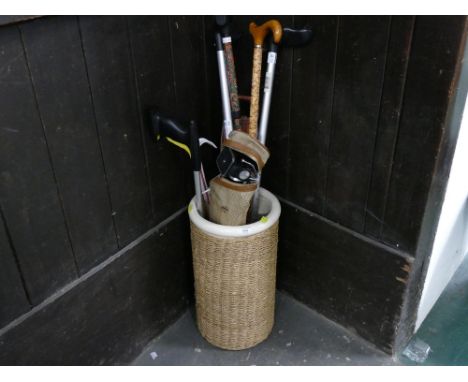 Ceramic and wicker wrapped stick stand with sticks and camera tripod