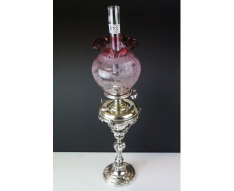 A silver plated oil lamp of classical form with drop in well Hinks burner and a cranberry floral decorated shade. 