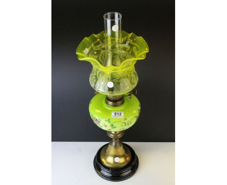 An antique oil lamp with floral green well raised on a brass and black ceramic base,with an art nouveau shade.