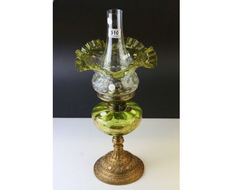 An antique French oil lamp with gilt metal base a green glass well with gilded floral decoration and a frilled edged shade. 