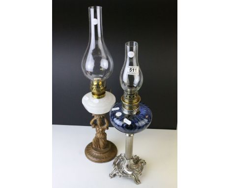 An Art Nouveau style oil lamp with scrolling base raised on a reeded column with blue glass well and chimney together with an