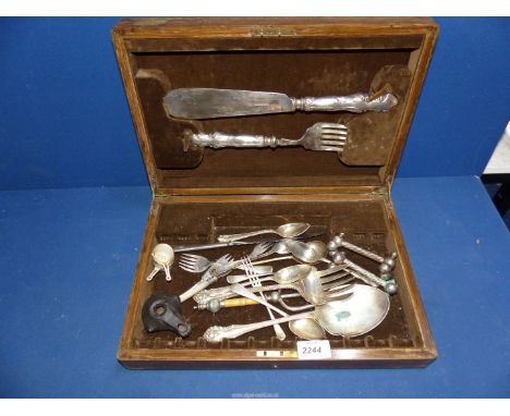 A wooden cutlery box with miscellaneous plated cutlery including fish servers, grapefruit spoons etc., plus a small oil lamp 