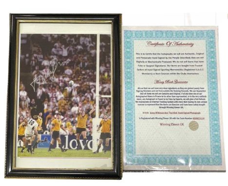 RUGBY INTEREST: A framed and glazed colour photograph, bearing the signature of England's Jonny Wilkinson, as he scores the w