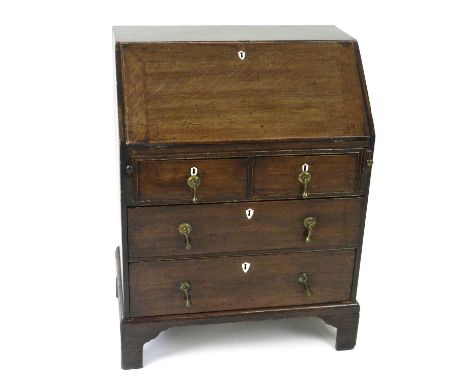 A small, well proportioned, George III oak bureau, with shield-shape bone escutcheons, the fall above two short and two long 