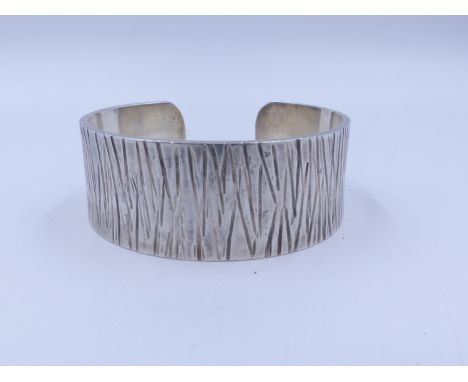 A GUILD OF HANDICRAFT SILVER CUFF BANGLE WITH BARK EFFECT FINISH. HALLMARKED LONDON 2005. TOTAL WEIGHT APPROX 84g. 