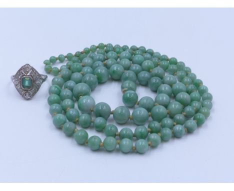 An 84cm (33") CONTINUOUS GRADUATED AND KNOTTED STRAND OF GREEN JADE BEADS. WEIGHT 57 GRAMS TOGETHER WITH AN 18ct STAMPED WHIT