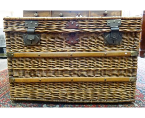 A large wicker trunk, early 20th century, with wooden battens, gilt metal mounts, hasps and lockplates, hinged top and interi