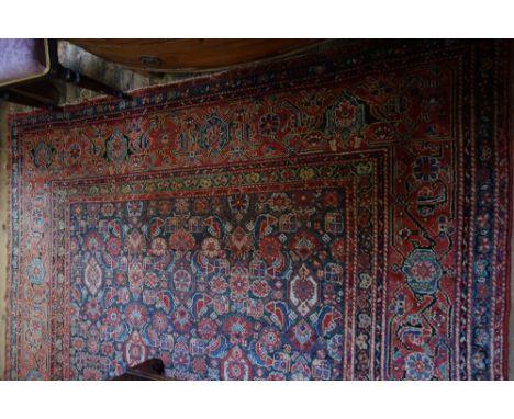 A Hamadan carpet, with an allover design of flowers and leaves within a red main border, 520cm x 215cm. 