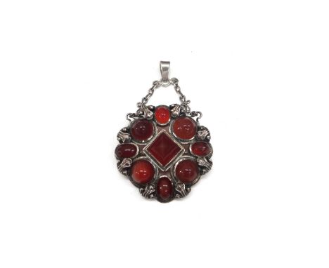 A cornelain set pendant brooch, in a shaped circular Arts & crafts design, mounted with a curved pyramid shaped cornelain to 
