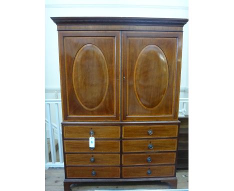 A George III style mahogany linen press, 19th century, satinwood banded boxwood and ebony strung, enclosed by a pair of oval 