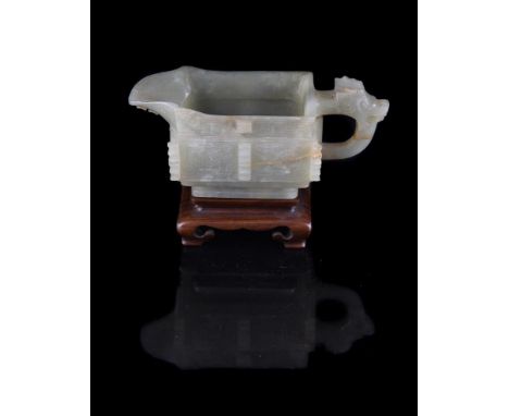 A Chinese celadon jade archaic style pouring vessel, Qing Dynasty, with carved handle and sides, brown and mottled white incl