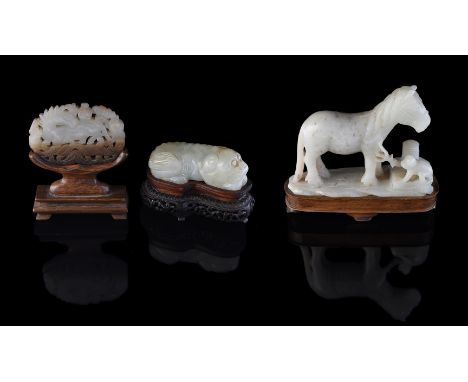 A Chinese celadon jade of a recumbent lion, Qing Dynasty, approximately 7cm long x 2. 7cm high x 3.5cm deep, fitted carved wo