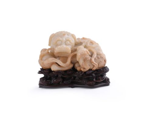 An attractive Chinese white and brown jade carving of a Buddhist and pup lion, a brocade ball held between the lions paws and