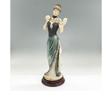 Cream color matte figure of a lady in an elegant dress with dark teal skirt and black textured bodice. She is holding a powde