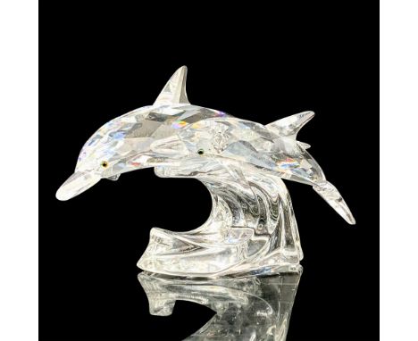 A clear crystal figure depicting a mother and child dolphin swimming side by side over a wave. Melon colored crystals are use