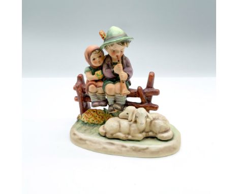 Hand-painted figurine depicting a boy and girl sitting on a fence with two lambs. Goebel backstamp on the bottom. Dimensions: