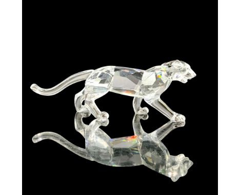 A clear crystal figure of a leopard in a stance that is prepared to pounce. Swarovski backstamp. This item has its original b