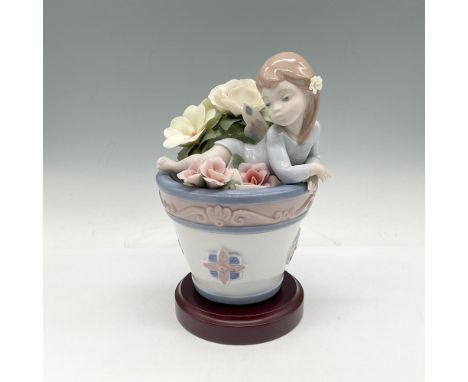 Glazed figural with a dreamy expression amidst flowers. Lladro backstamp. This item has a base included 1"H x 4" dia. Artist: