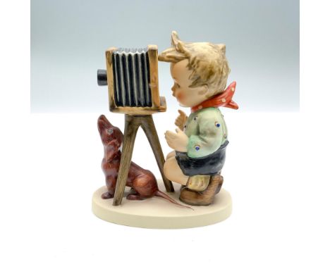 Hand-painted figurine depicting a boy with an old-fashioned camera and a dog. Goebel backstamp on the bottom. Issued: 1948Dim