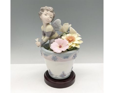 This adorable young glazed figural with wings sitting among large petaled flowers colored in pink, yellow and cream in a deco