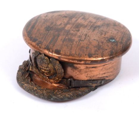 GREAT WAR - A BRASS TRENCH ART SNUFF BOX IN THE FORM OF A NAVAL OFFICER'S PEAKED CAP  with chin-strap, hinged base for snuff,