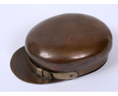 GREAT WAR - A LARGE BRASS TRENCH ART SNUFF BOX IN THE FORM OF A PEAKED CAP  with chin-strap and hinged base for snuff, 13cm l