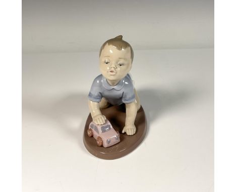 Glossy porcelain figure of a joyful boy playing with his toy car, evoking childhood memories. Lladro backstamp. Artist: Joan 