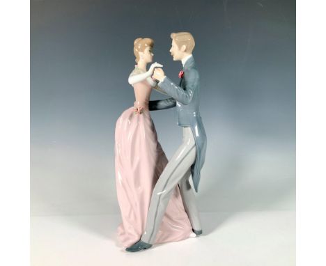 Glossy finished couple dancing. She is dressed in a pink gown and white gloves. He is wearing a grey suit with tails. Lladro 