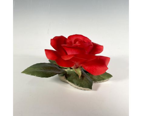 A striking red rose bursts into bloom from its stem, surrounded by five vibrant green leaves. Boehm backstamp. Marked USA. Is