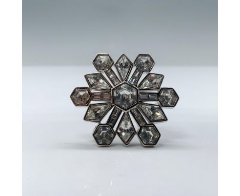 This brooch features faceted crystals in a geometric star pattern radiating from a central stone. This item has its original 