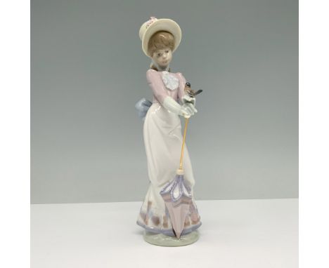 Glossy finish porcelain figurine depicting a woman in Victorian-style attire holding an umbrella and a small bird in her hand