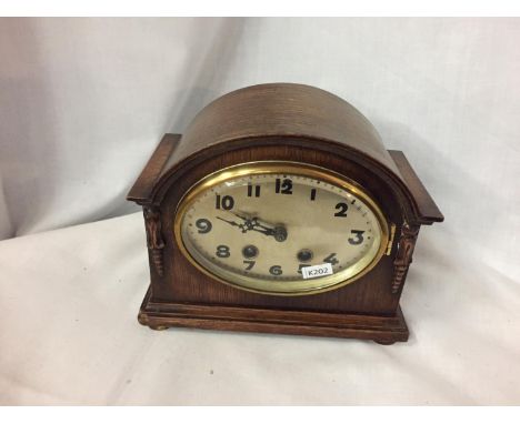 A VINTAGE WOODEN CASED CLOCK WITH A BRASS OVAL FACE, WITH PENDULUM, NO KEY. WORKING AT TIME OF LOTTING UP 